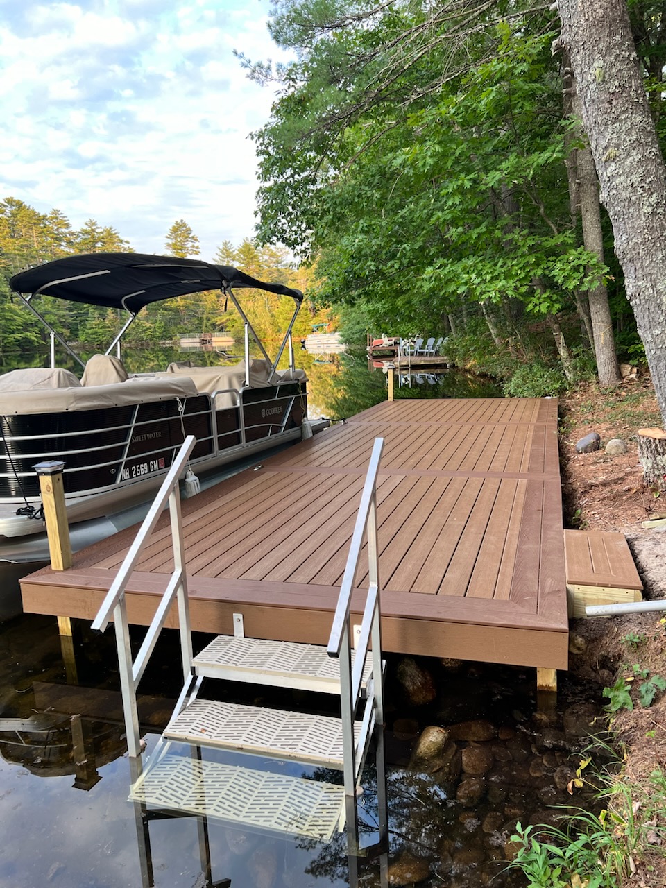 Custom-built dock with composite decking on a scenic New Hampshire lake, designed and installed by Dock Dogs Construction